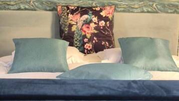A bed with a floral pillow, a green pillow, and a blue blanket.