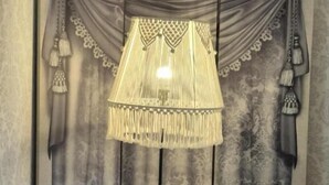 Una habitación con dos sillones grises, una mesita blanca con una caja de pañuelos y una lámpara de pie con pantalla flequecilla.