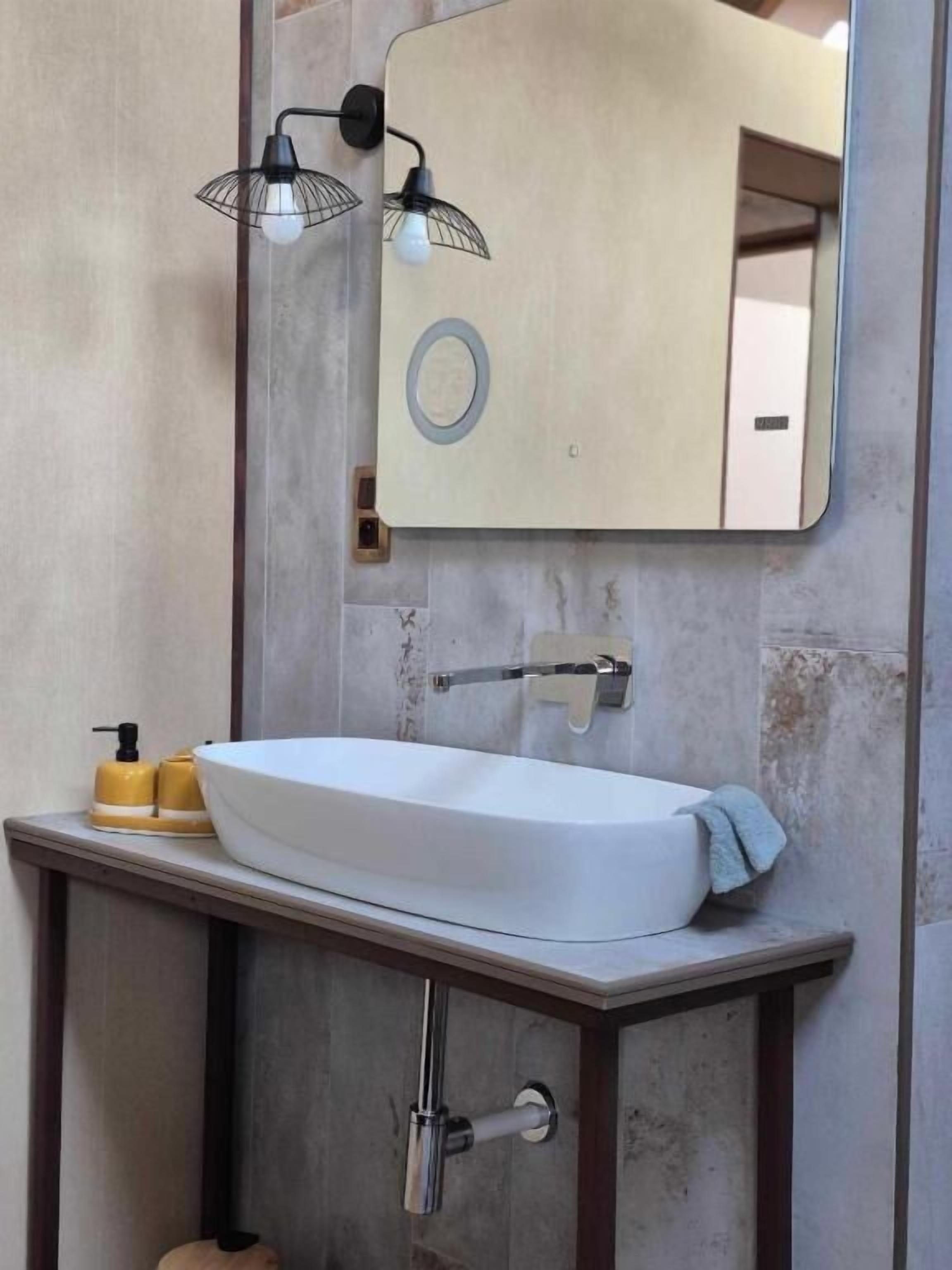 Un baño con un lavabo blanco, un espejo y dos luces empotradas.