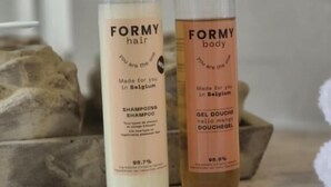 Dos botellas de productos FORMY para cabello y cuerpo sobre una superficie de mármol.