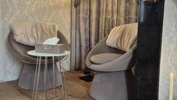 A modern living room with two armchairs, a small round table, a decorative lamp, and a fireplace.