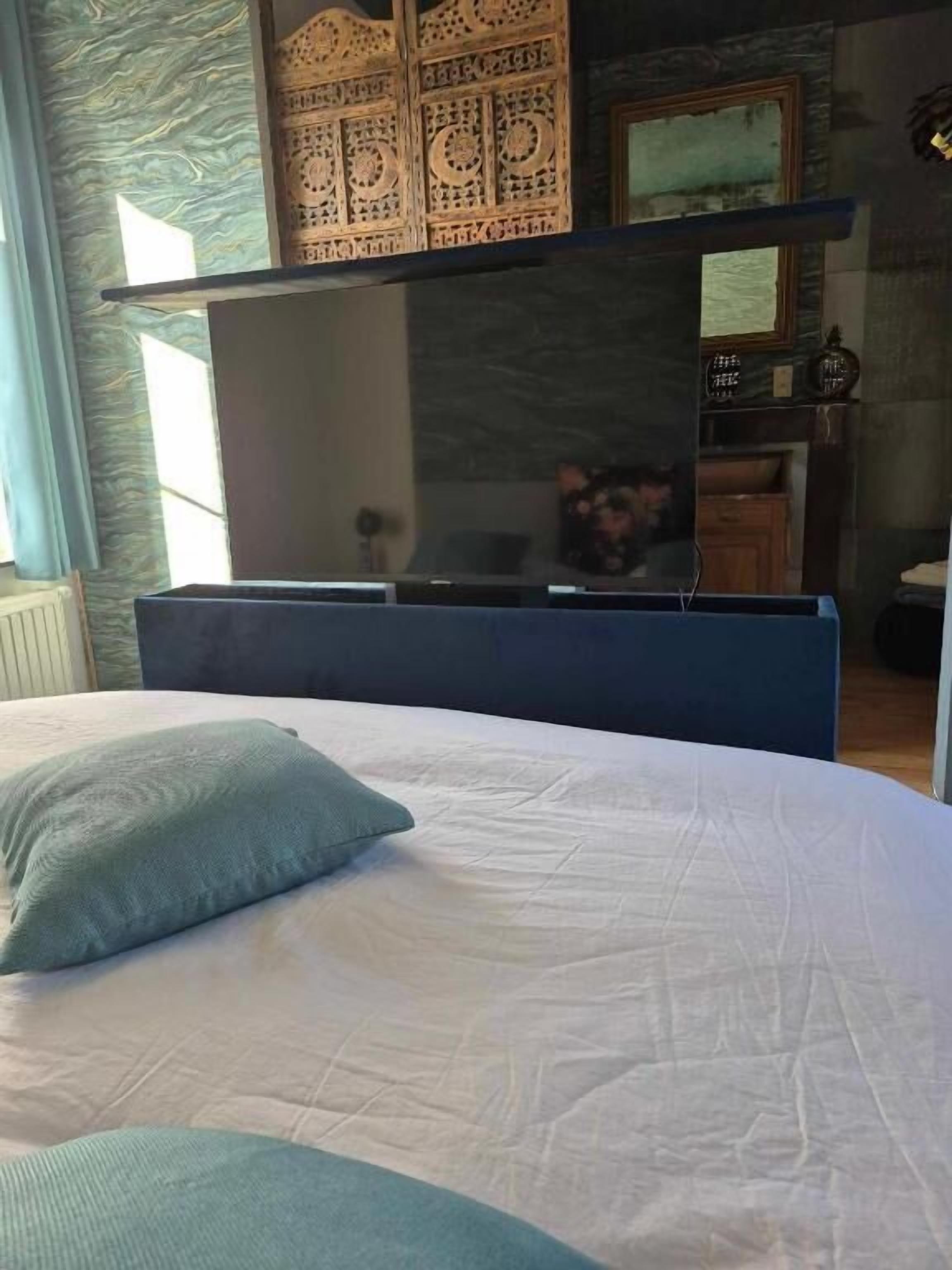 Ein Schlafzimmer mit einem Bett, einem blauen Kopfteil, einer Wandverkleidung, einem Spiegel und einer Uhr.