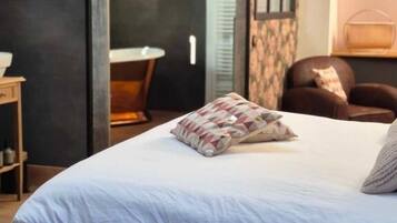 A bedroom with a wooden bed, a bedside table, a chair, and a small table with a lamp.
