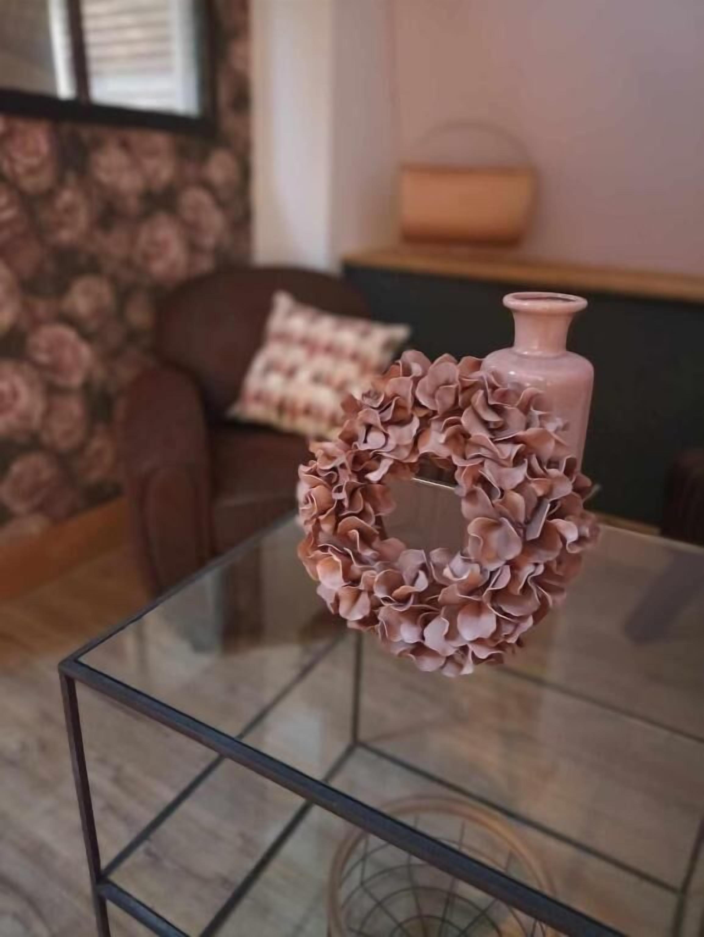 Una mesa de vidrio con un florero rosa encima.