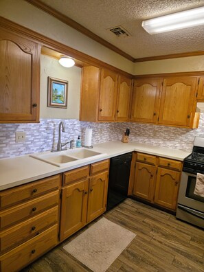 A kitchen with wooden cabinets, a sink, a dishwasher, and a stove.