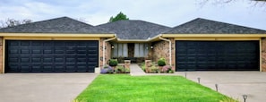 A two-car garage house with a stone facade and a well-maintained lawn.