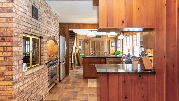Een keuken met een bakstenen muur, houten kastjes en een centraal eiland.