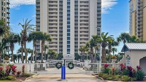 Un hotel moderno con una torre centrale, circondato da palme e un ingresso carrabile.