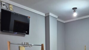 Une pièce avec un fauteuil suspendu en bois, un téléviseur fixé au mur et une échelle en bambou.