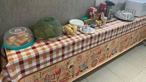 Une table de buffet recouverte d’une nappe à carreaux, sur laquelle sont disposés différents plats et une variété de condiments.