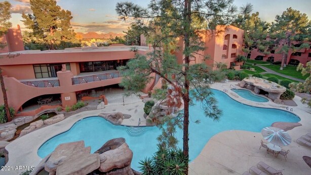 Ein Resort mit mehreren Schwimmbecken, einem Innenhof und einem Gebäude mit Balkonen.