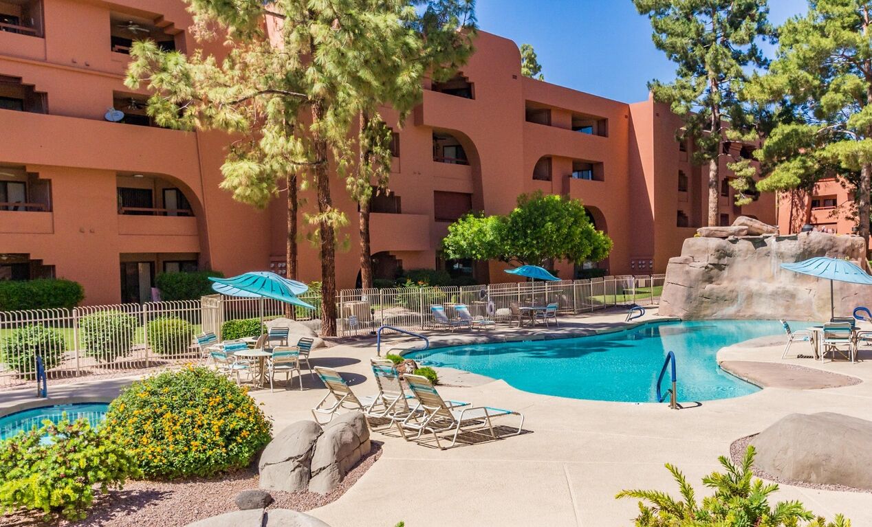 Un hotel con zona de piscina, incluyendo sillones de descanso y sombrillas.