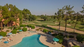 Ein Resort mit Schwimmbad, Liegestühlen und einem Golfplatz im Hintergrund.