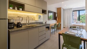 A modern kitchen with built-in appliances, a dining area with a table and chairs, and a balcony with a view of the surrounding buildings. - Modern Studio in Lapa With Pool and gym R1205 (Nova Iguaçu)