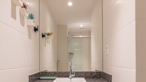 A bathroom with a white vanity, a mirror, and a sink. - Modern Studio in Lapa With Pool and gym R1205 (Nova Iguaçu)