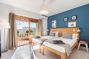 Ein Schlafzimmer mit zwei Betten, einem Balkon und Blick auf Gebäude.