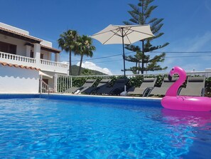 Ein Swimmingpool mit Liegestühlen und einem Flamingo-Schwimmpferd.