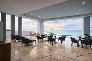 Uma área de estar ampla ao ar livre, com vista para o mar, com móveis modernos e piso em azulejo.