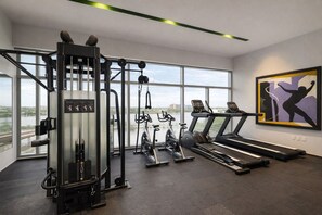 A gym with cardio machines, weight training equipment, and large windows offering a view of the outdoors. - Condo Premium - Malecón | Vista al mar | Grupos 6+ (Mazatlán)