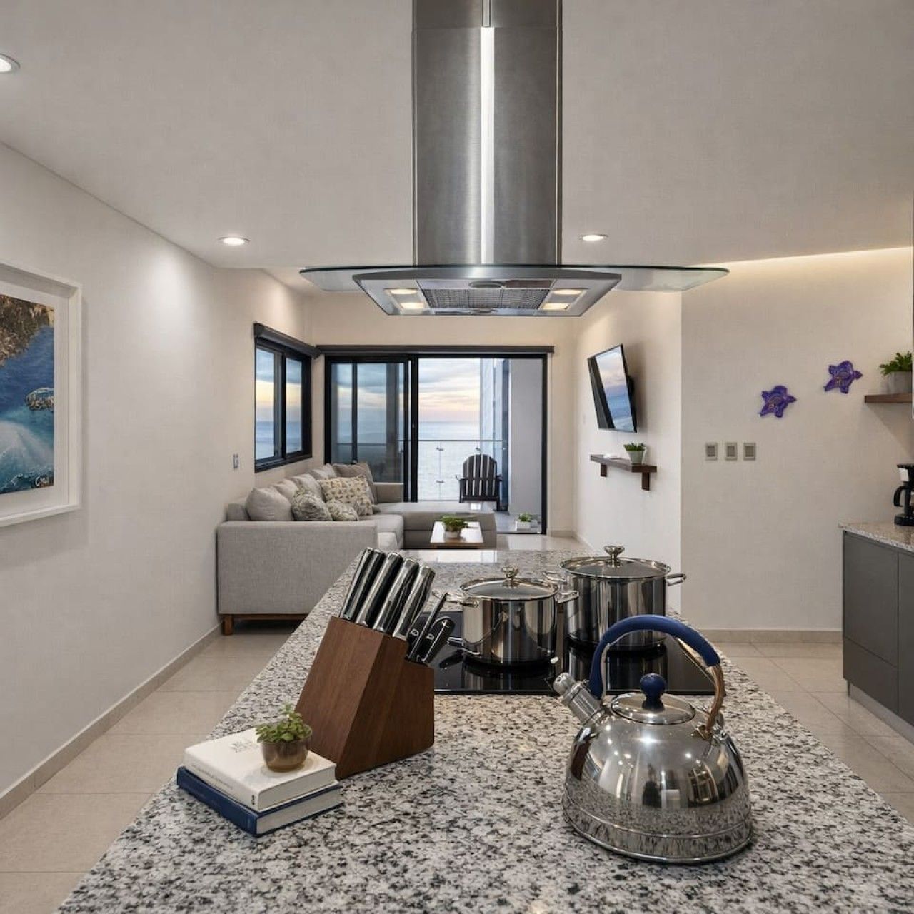 A modern kitchen with a stainless steel range hood, granite countertops, and a kettle.
