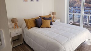 A bedroom with a large bed, two bedside tables, a window with a view, and three wall-mounted artworks. - Patricias Park (Mendoza)