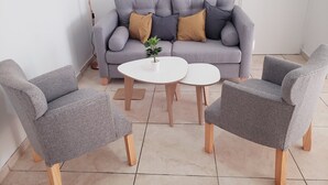 A living room with a grey sofa, two grey armchairs, and a small white table with a plant. - Patricias Park (Mendoza)