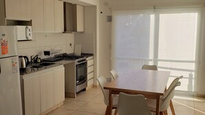 A modern kitchen with a dining area, featuring a large window, white cabinetry, and a tiled floor. - Patricias Park (Mendoza)