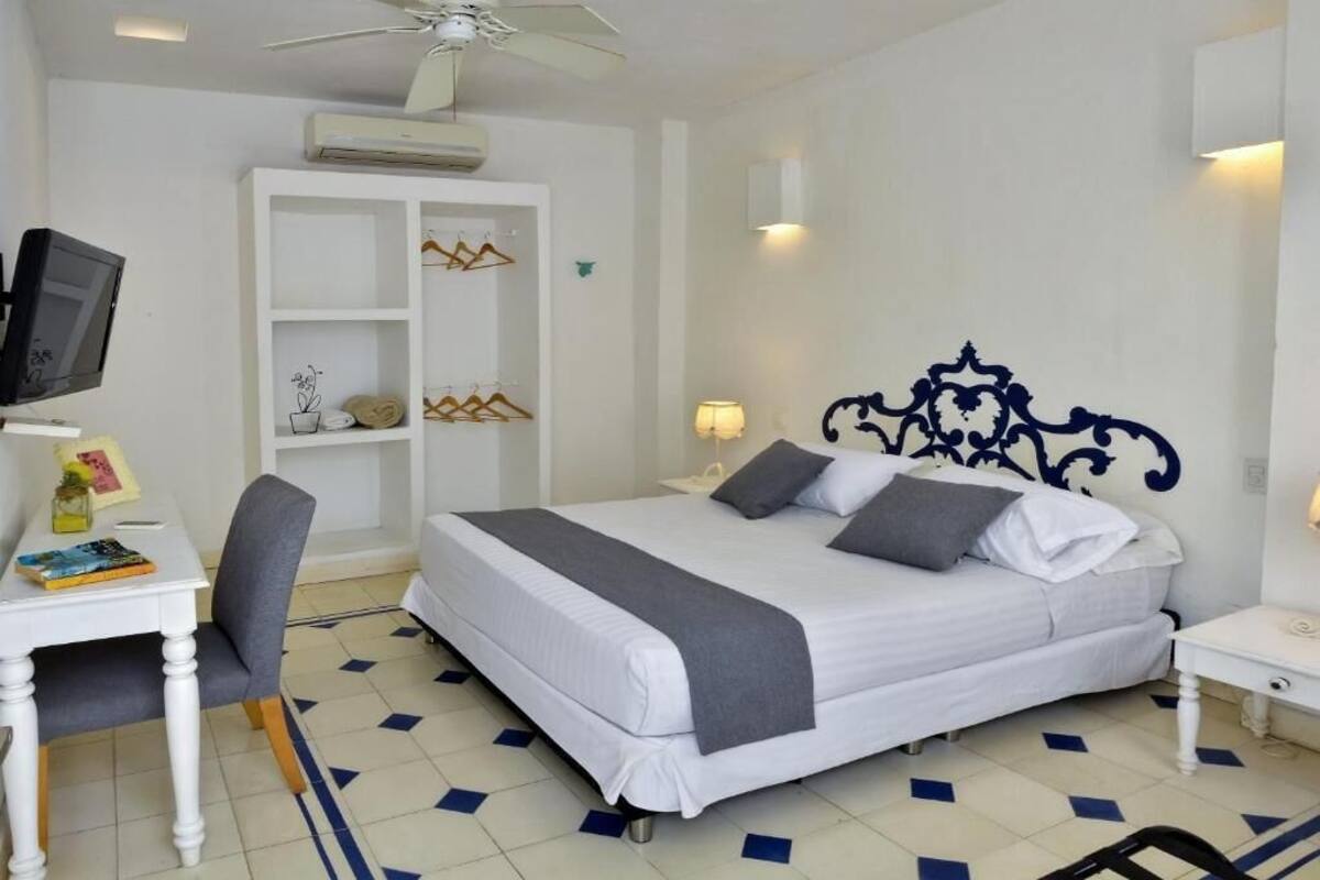 Ein ordentlich eingerichtetes Schlafzimmer mit Bett, Schreibtisch, Stuhl und Fernseher.
