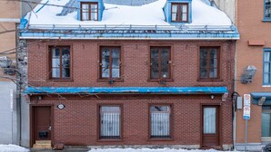 A two-story brick building with a blue roof and multiple windows. - La Cabine Du Phare (2-1116) (Québec City)