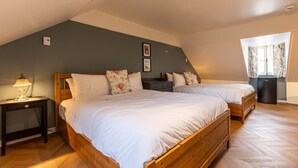 A bedroom with two wooden beds, a nightstand, a lamp, and a window with curtains.