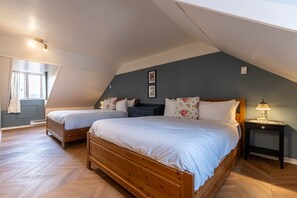 Een slaapkamer met twee houten bedden, een nachtkastje en een raam met gordijnen.