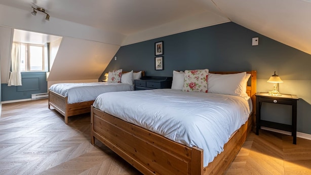 A bedroom with two wooden beds, a nightstand, and a window with curtains.