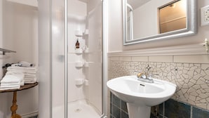 A bathroom with a shower, a sink, and a mirror.