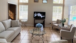 Ein geräumiges Wohnzimmer mit einem großen Fernseher, zwei Sofas, einem Couchtisch und einer Topfpflanze.
