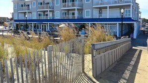 Ett hotell med flera våningar, balkonger, en överbyggd gångväg och ett område med sandstrand.