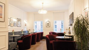 Un'area lounge moderna con comode sedute, un lampadario, opere d'arte incorniciate alle pareti e ampie finestre che lasciano entrare luce naturale.