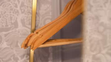 Una silla de madera con respaldo curvo y estructura metálica, ubicada frente a un fondo de papel tapiz estampado.