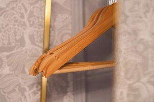 Una silla de madera con respaldo curvo y estructura metálica, ubicada frente a un fondo de papel tapiz estampado.