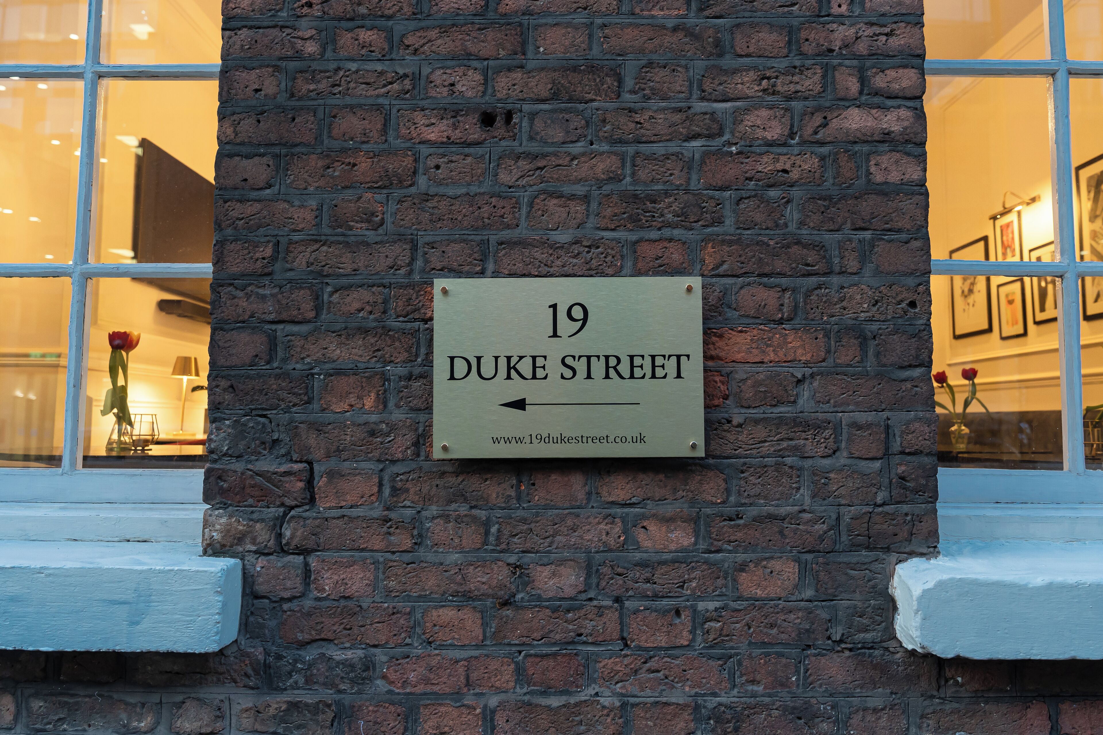 Naamplaatje voor 19 Duke Street met een pijltje en een website-URL.