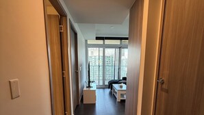 Ein moderner Flur mit dunklem Boden, Holztüren und Blick auf einen Balkon mit Stadtansicht.