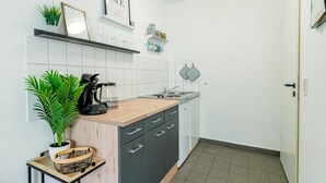 Une cuisine compacte avec un plan de travail en bois, une machine à café, un évier et une plante en pot.