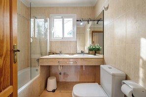 A bathroom with two sinks, a toilet, a shower, and a window. - Amazing Location & Value! (Sant Josep de sa Talaia)