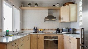 Eine Küche mit Holzausstattung, einer Edelstahl-Dunstabzugshaube, einer Mikrowelle und einem eingebauten Backofen.