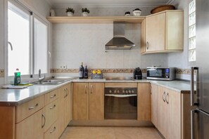 A kitchen with wooden cabinets, a stainless steel range hood, a microwave, and a built-in oven. - Amazing Location & Value! (Sant Josep de sa Talaia)