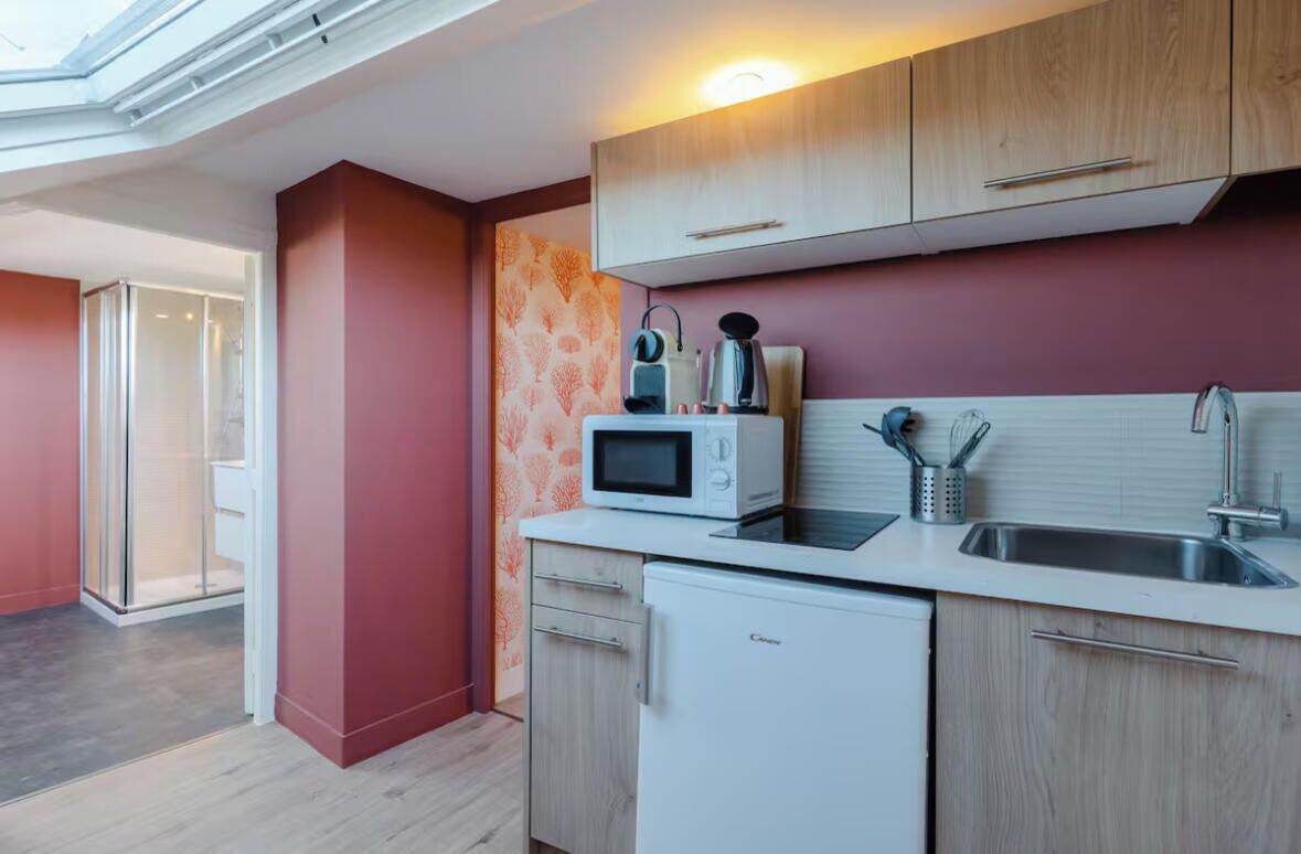 Una cocina compacta con microondas, tostadora y lavabo.