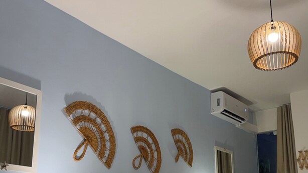 A hotel room with two beds, a bedside table with a lamp, a wall-mounted air conditioner, and a ceiling light fixture. - Pousada Mar da Vila (Cabo Frio)