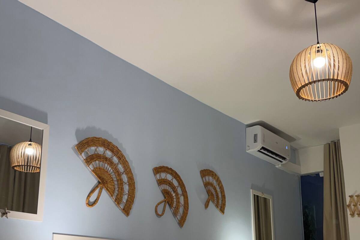 Hotelkamer met twee bedden, een nachtkastje met een lamp, een wandairconditioner en een plafondlamp.