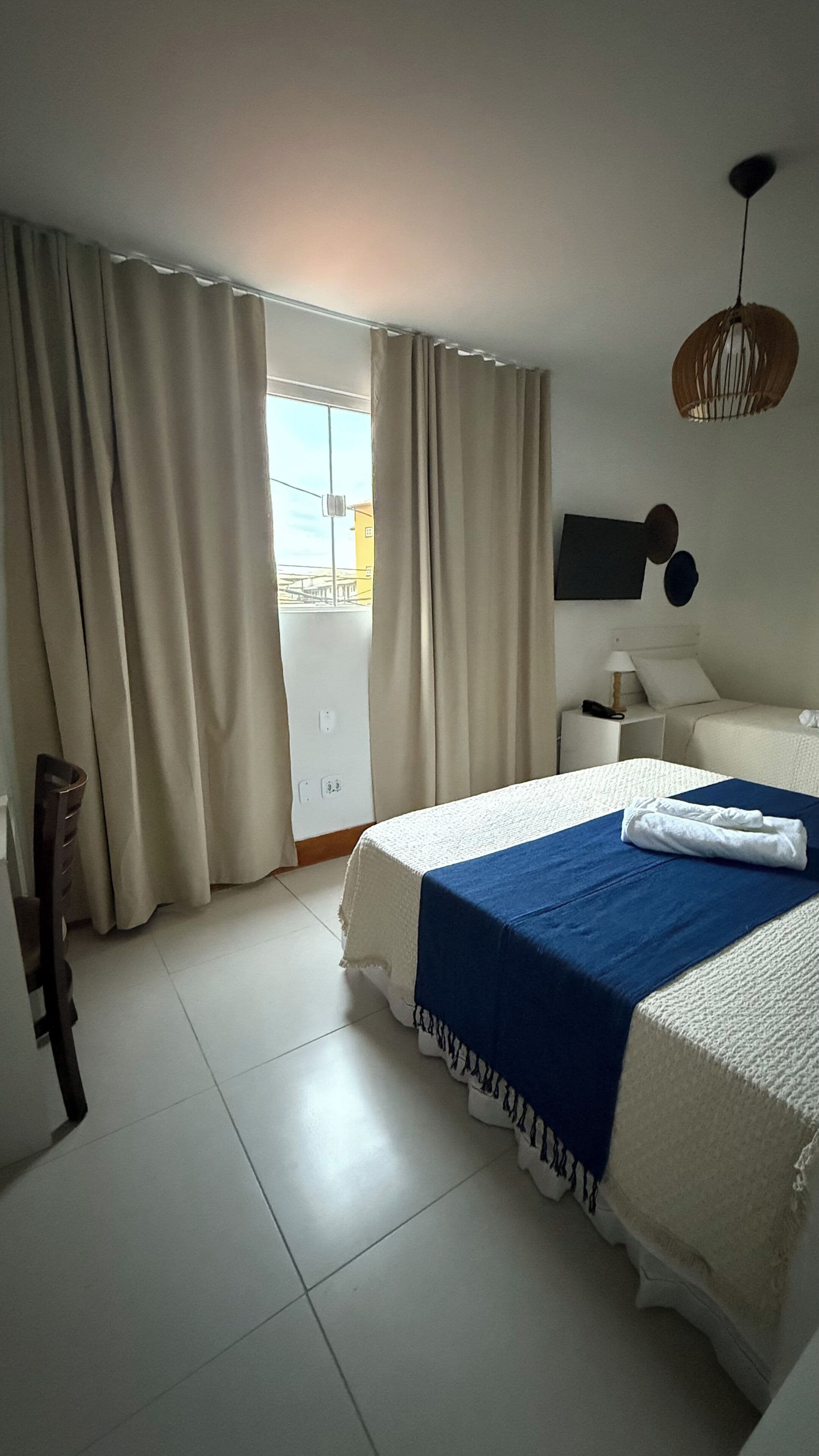 Une chambre d’hôtel avec un grand lit, une table de chevet, une chaise, une armoire et une vue sur l’extérieur.