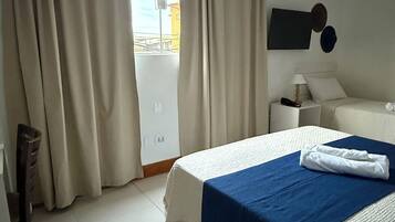 Une chambre d’hôtel avec un grand lit, une table de chevet, une chaise, une armoire et une vue sur l’extérieur.