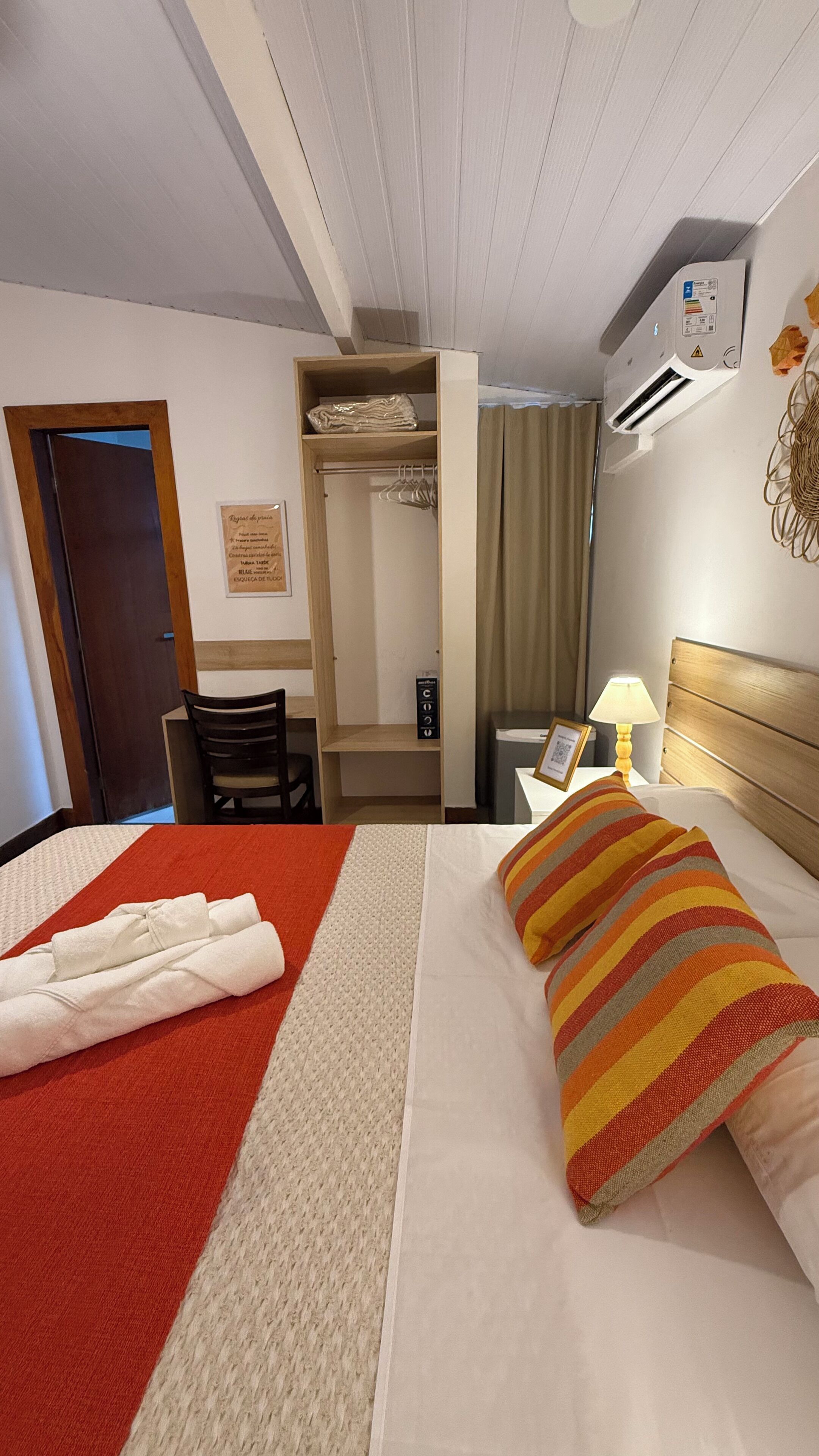 Une chambre d’hôtel comprenant un lit, un bureau, une chaise, une armoire et une table de chevet avec une lampe.